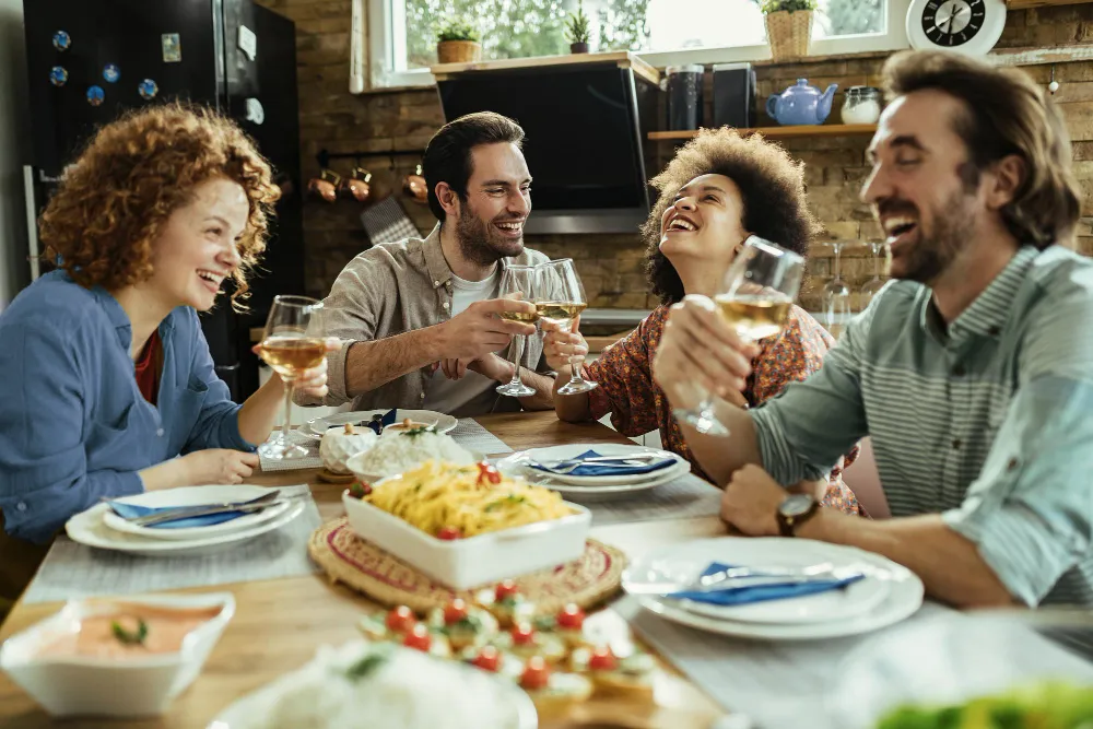 Friends laughing and toasting around a dinner table